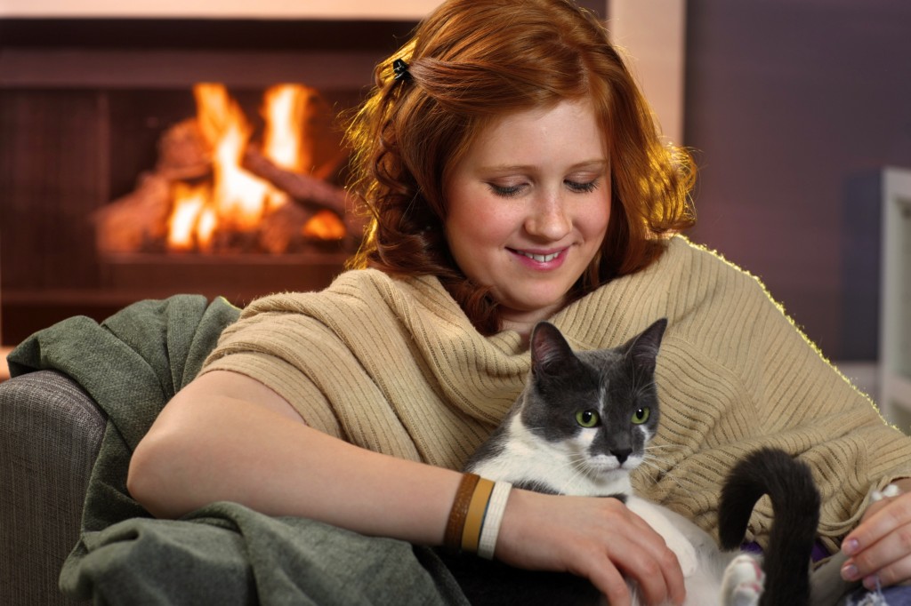 Smiling teenage girl loving her cat at home