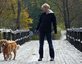 woman walking dog on bridge