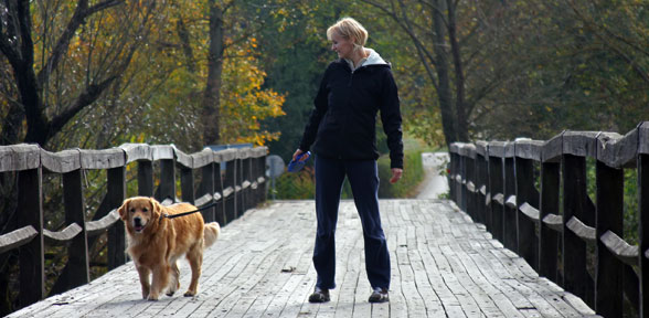 woman walking dog on bridge